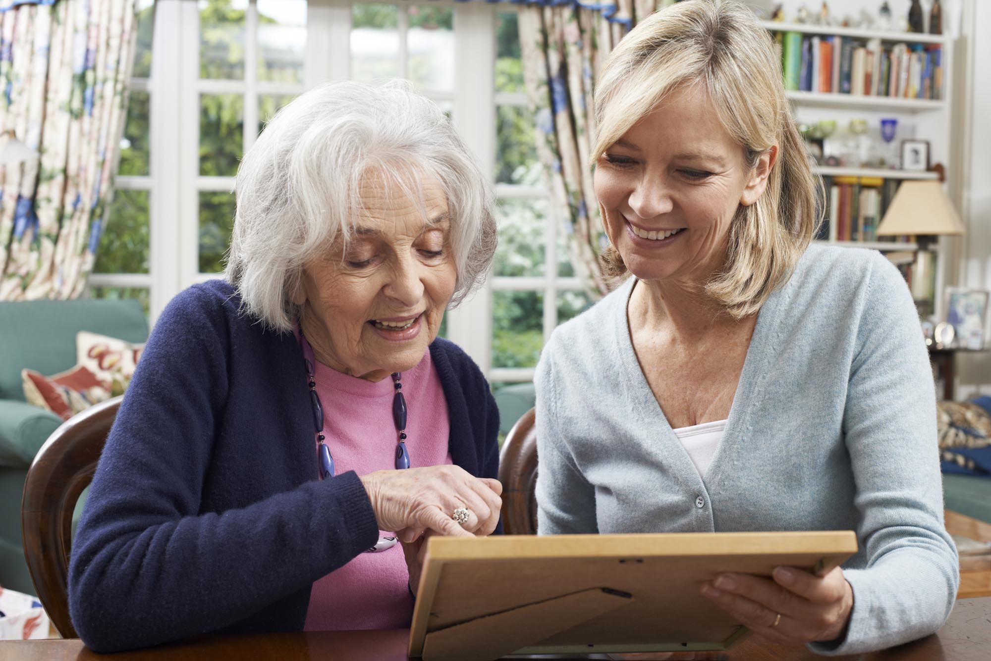 Senior Woman Looks At Photo With private caregiver