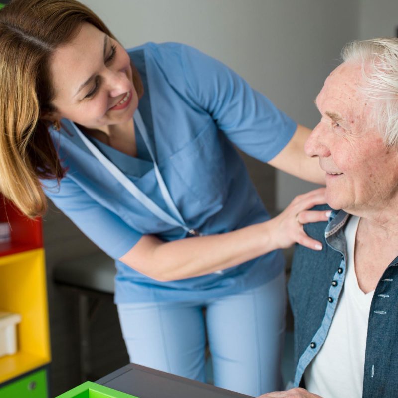 Happy caregiver assisting senior man with Parkinson's Disease